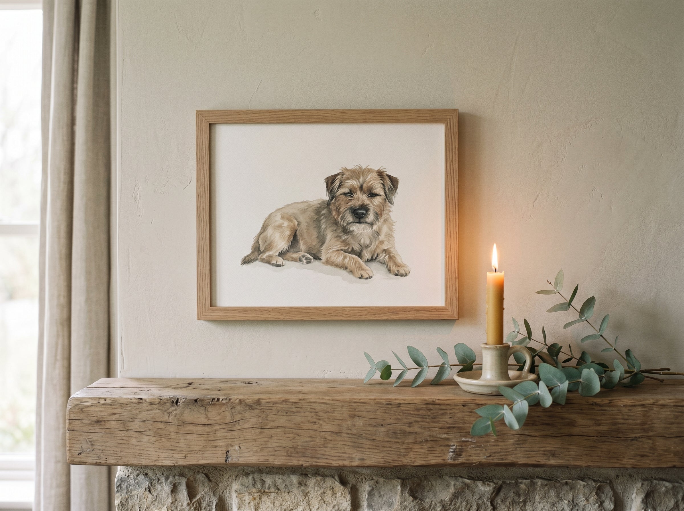 A framed watercolour portrait on a mantel with a candle and eucalyptus